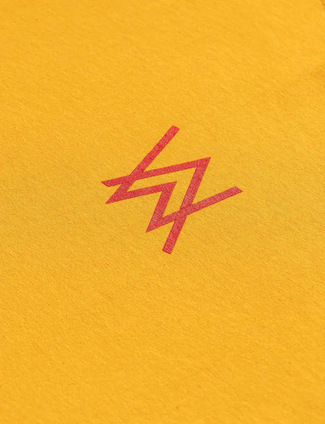 Close-up of a red Alan Walker logo printed on a bright yellow t-shirt fabric.