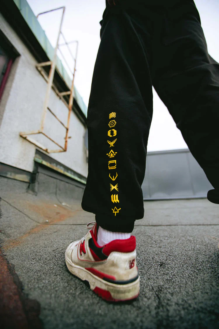 Person wearing black Walkerverse sweatpants with a detailed leg logo design.
