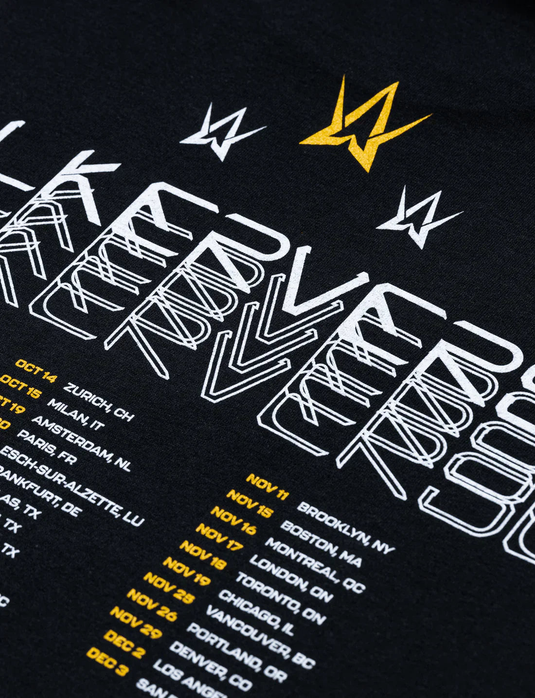 Detailed view of a black t-shirt's back with 'Walkerverse' tour dates in golden and white print and multiple small Alan Walker logos.